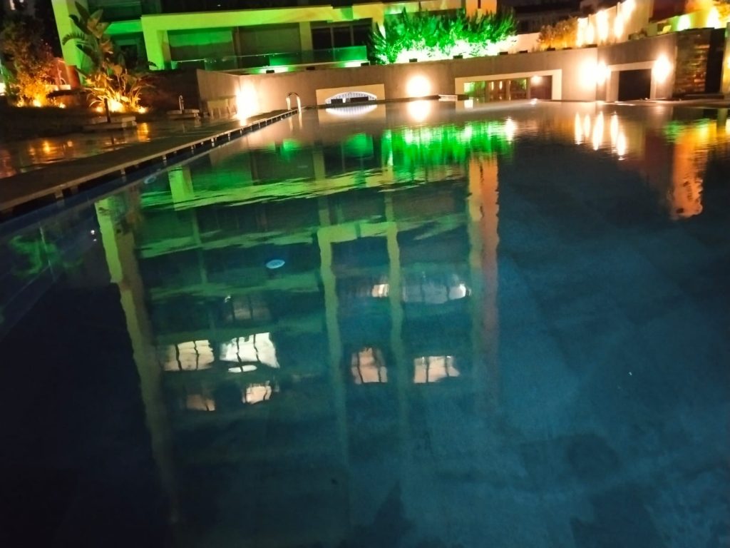 Temiz ve berrak havuz suyunun yüzeyine odaklanan bir fotoğraf. Su yüzeyi düzgün ve ışıkların suya yansıması net bir şekilde görünür.